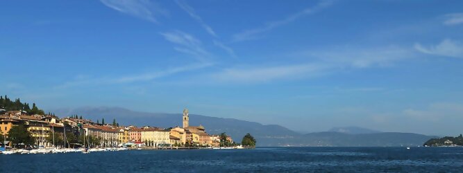 Trip Florenz beliebte Urlaubsziele am Gardasee -  Mit einer Fläche von 370 km² ist der Gardasee der größte See Italiens. Es liegt am Fuße der Alpen und erstreckt sich über drei Staaten: Lombardei, Venetien und Trentino. Die maximale Tiefe des Sees beträgt 346 m, er hat eine längliche Form und sein nördliches Ende ist sehr schmal. Dort ist der See von den Bergen der Gruppo di Baldo umgeben. Du trittst aus deinem gemütlichen Hotelzimmer und es begrüßt dich die warme italienische Sonne. Du blickst auf den atemberaubenden Gardasee, der in zahlreichen Blautönen schimmert - von tiefem Dunkelblau bis zu funkelndem Türkis. Majestätische Berge umgeben dich, während die Brise sanft deine Haut streichelt und der Duft von blühenden Zitronenbäumen deine Nase kitzelt. Du schlenderst die malerischen, engen Gassen entlang, vorbei an farbenfrohen, blumengeschmückten Häusern. Vereinzelt unterbricht das fröhliche Lachen der Einheimischen die friedvolle Stille. Du fühlst dich wie in einem Traum, der nicht enden will. Jeder Schritt führt dich zu neuen Entdeckungen und Abenteuern. Du probierst die köstliche italienische Küche mit ihren frischen Zutaten und verführerischen Aromen. Die Sonne geht langsam unter und taucht den Himmel in ein leuchtendes Orange-rot - ein spektakulärer Anblick.